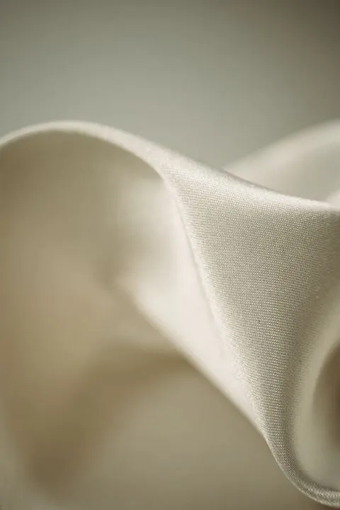 Close-up of a soft fold of ivory silk fabric with a fine visible weave